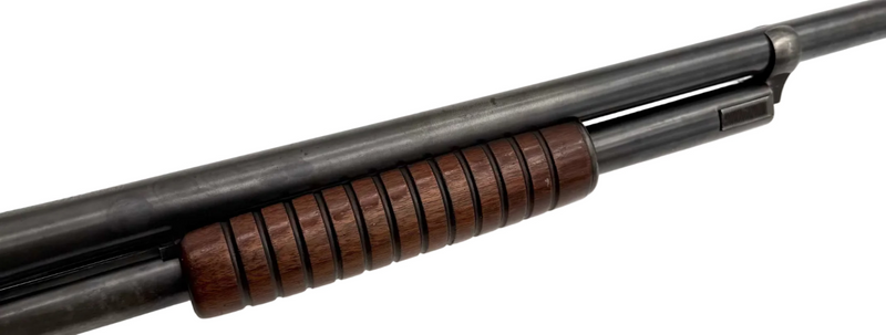 Remington Model 10 12 gauge pump-action shotgun with wooden stock and barrel, viewed from the side.